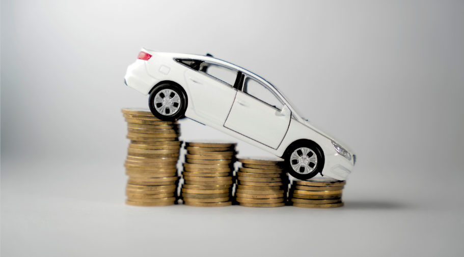 Toy car on top of declining stacks of coins representing car prices falling